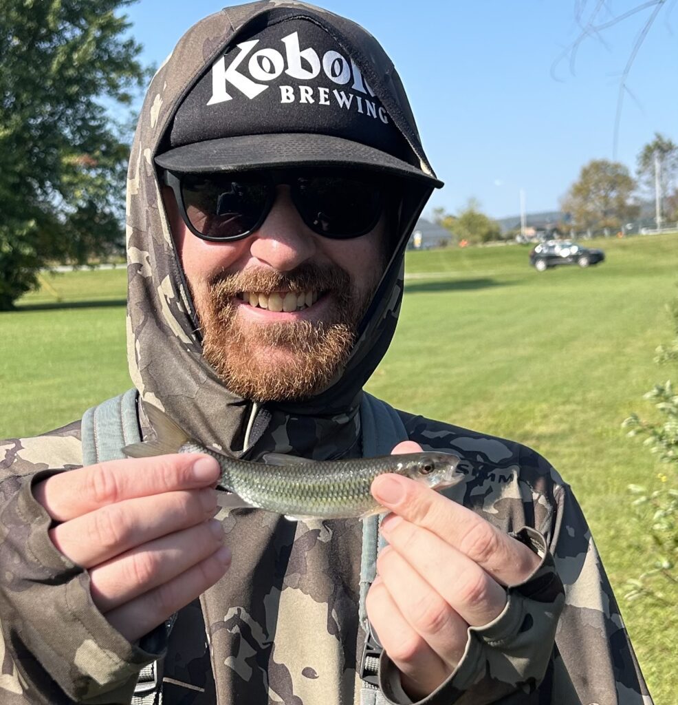 A man holding a small minnow caught while fishing